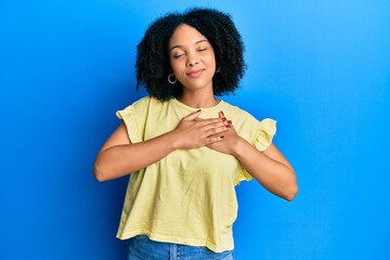 Sticker - Young african american girl wearing casual clothes smiling with hands on chest with closed eyes and grateful gesture on face. health concept.