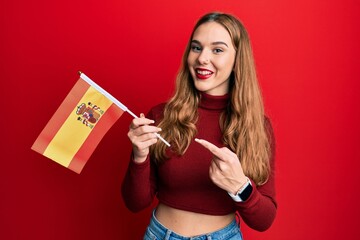 Sticker - Young blonde woman holding spain flag smiling happy pointing with hand and finger