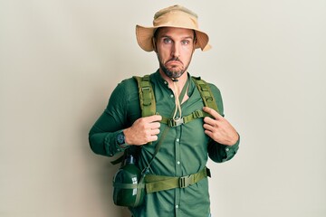 Wall Mural - Handsome man with beard wearing explorer hat and backpack depressed and worry for distress, crying angry and afraid. sad expression.