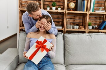 Young man surprising his girlfriend with birthday gift at home.