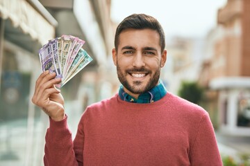 Young hispanic man smiling happy standing at the city.