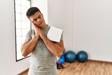 Poster - Young hispanic man wearing sportswear and towel at the gym sleeping tired dreaming and posing with hands together while smiling with closed eyes.