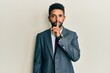 © Krakenimages.com - Handsome hispanic man with beard wearing business suit and tie asking to be quiet with finger on lips. silence and secret concept.