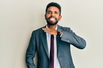 Wall Mural - Handsome hispanic man with beard wearing business suit and tie cutting throat with hand as knife, threaten aggression with furious violence