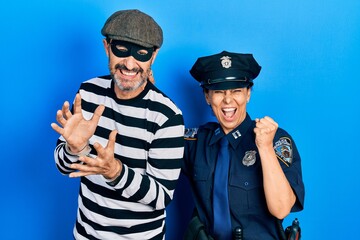 Canvas Print - Middle age couple of hispanic woman and man wearing thief and police uniform very happy and excited doing winner gesture with arms raised, smiling and screaming for success. celebration concept.