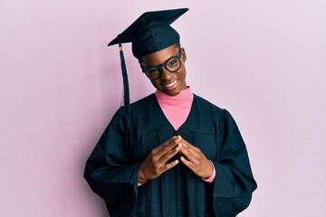 Poster - Young african american girl wearing graduation cap and ceremony robe hands together and fingers crossed smiling relaxed and cheerful. success and optimistic