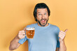 © Krakenimages.com - Middle age caucasian man drinking a jar of beer pointing thumb up to the side smiling happy with open mouth