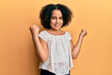 Sticker - Young little girl with afro hair wearing casual clothes excited for success with arms raised and eyes closed celebrating victory smiling. winner concept.