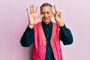 Canvas Print - Middle age indian man wearing traditional indian clothes showing and pointing up with fingers number seven while smiling confident and happy.