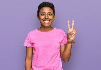 Wall Mural - Young african american woman wearing casual clothes showing and pointing up with fingers number two while smiling confident and happy.