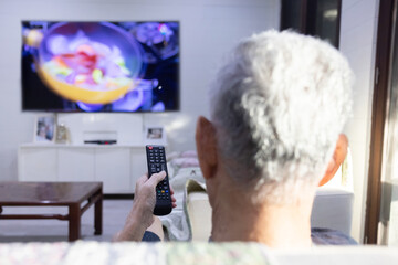 Asian Mature Man Using Television Remote Control in the Living Room