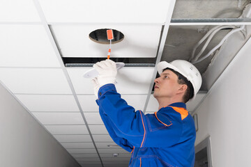 Wall Mural - the electrician installs the lighting in the suspended ceiling