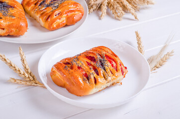 Fresh tasty bun with berry filling on white plate on wooden background