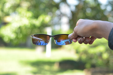 man hand holding Black Glasses or sun glasses with vintage style and blurred background