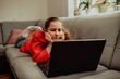 © Minet - little girl, a preschooler, uses a laptop to study at home. the child smiles happily and receives knowledge remotely. digital concept of e-learning. Distance e-learning.