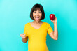 © luismolinero - Pregnant woman holding an apple isolated on blue background celebrating a victory in winner position