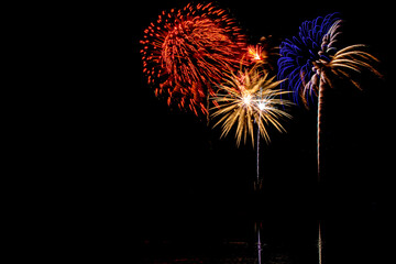 Wall Mural - Holiday fireworks above water with reflection in the water