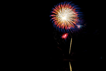 Wall Mural - Holiday fireworks above water with reflection in the water