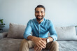 © Stock 4 You - Portrait of indian man toothy smiling to camera sitting on sofa webcam view