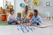 © New Africa - Mother and little girls taping sticker hopscotch on floor at home