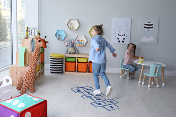 Canvas Print - Cute little girls playing hopscotch at home