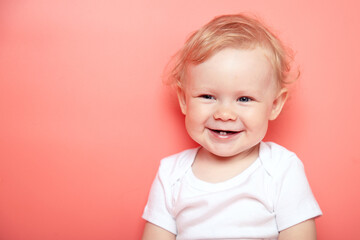 portrait caucasian curly blond smiling baby girl with two teethon pink background wearing in white t-shirt. copy space.