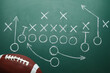 © New Africa - Rugby ball and drawn American football strategy game on green chalkboard, top view