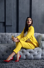 Wall Mural - Beautiful businesswoman with glass of champagne on sofa indoors. Luxury lifestyle