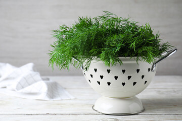 Fresh dill in colander on white wooden table