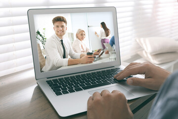 Poster - Man attending online video conference via modern laptop at table, closeup