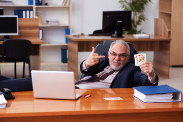 Canvas Print - Old male employee playing cards at workplace