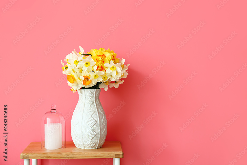 Vase with narcissus flowers on table in room