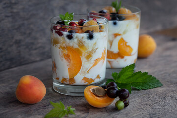 Two glasses of yogurt with apricots, strawberries and black currants