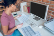 A woman in eyeglasses working on a computer and looking busy
