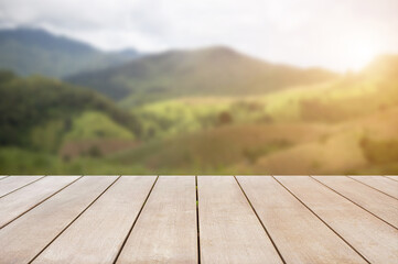 Empty old wooden table in front of blurred beautiful mountain and meadow with beautiful sunrise background of nature. Can be used for display or montage for show your products.