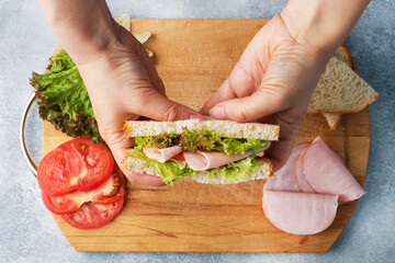 Delicious healthy sandwich for a snack breakfast in women hands. Toast bread tomato ham leaf salad.