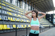 © RomanR - pretty slim woman in sport wear resting after hard workout near chairs on modern stadium