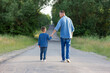 father and son walk along the road holding hands