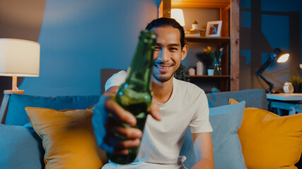 Wall Mural - Happy young asia man looking at camera enjoy night party event online with friends toast drink beer via video call online in living room at home, Stay at home quarantine, Social distancing concept.