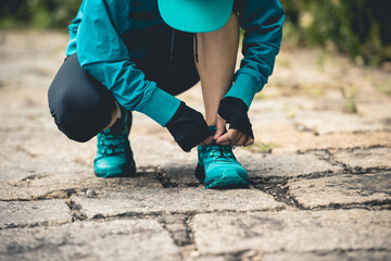 Wall Mural - woman runner tying shoelace on trail