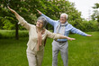 © Studio Romantic - Happy smiling active healthy senior family retired couple making wings with hands spreading arms like plane and flying during rest in green park or forest outdoors. Retirement lifestyle concept