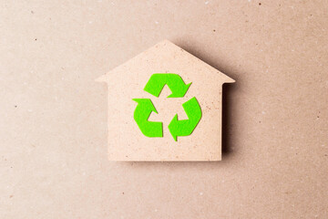 Ecological house with recycling symbol on brown paper background.