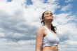 low angle view of young happy woman in crop top against blue sky with clouds