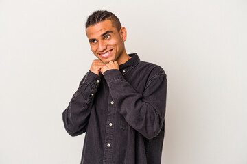 Young venezuelan man isolated on white background keeps hands under chin, is looking happily aside.