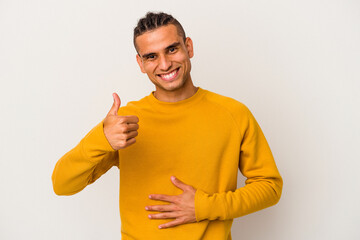 Young venezuelan man isolated on white background touches tummy, smiles gently, eating and satisfaction concept.