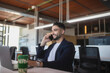 © ADDICTIVE STOCK - Smiling businessman talking on smartphone in office