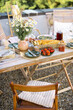 Beautifully served wooden table in natural boho style outdoors. Dining table decorated with field flowers, dishes and fresh food