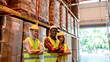 © BigBlues - Portrait of staff at distribution warehouse.Manager and worker logistics team with crossed arms.Worker man and woman delivery service team of employees over warehouse background
