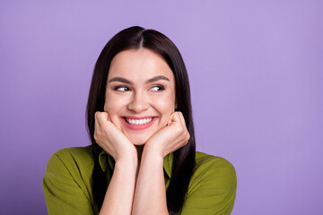 Photo of excited sweet young lady dressed green clothes smiling arms cheekbones looking empty space isolated purple color background