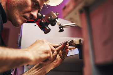 Concentrated man moving hand file over silver item